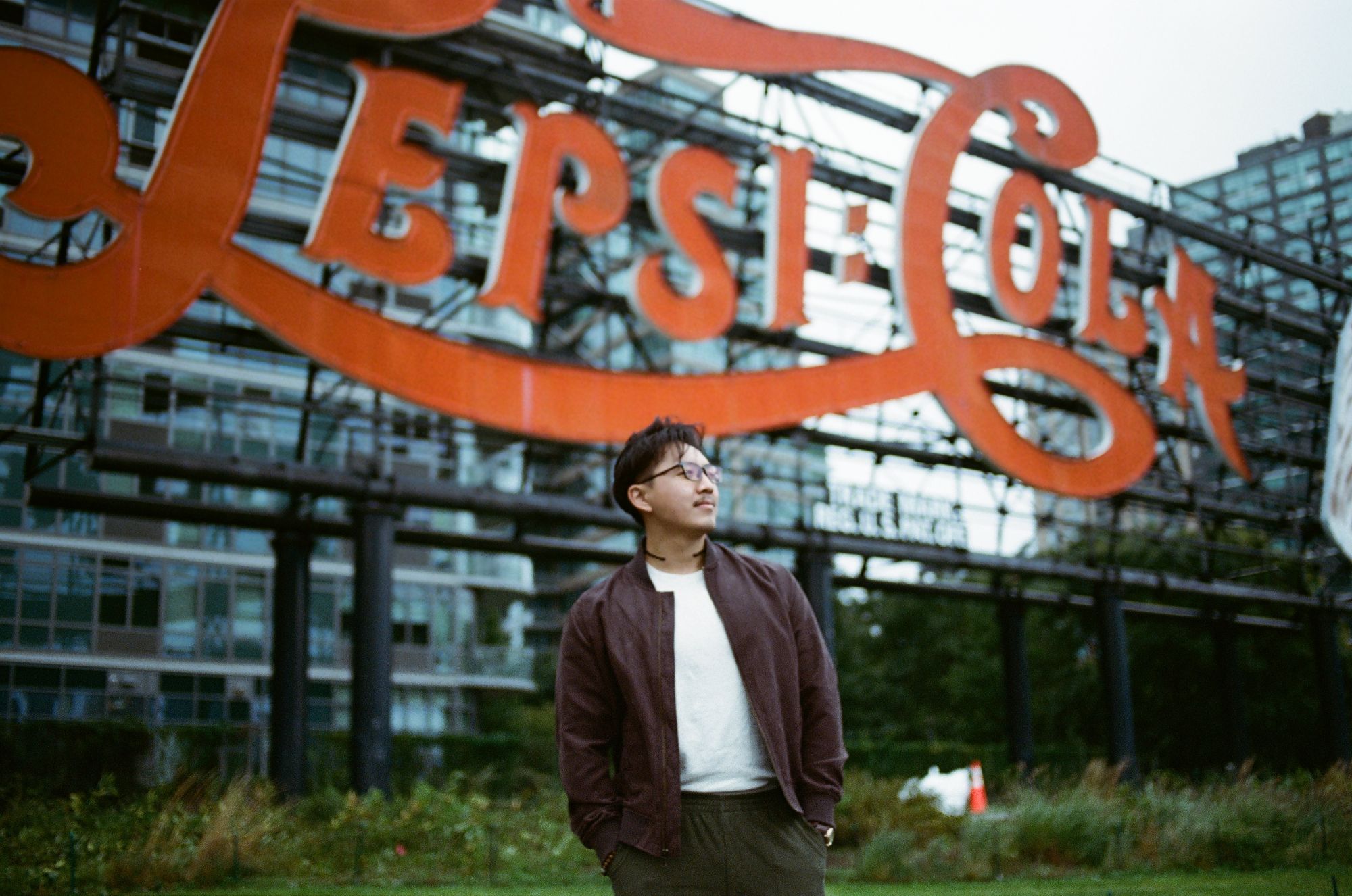 Portrait of Stephen Mok standing in front of a large vintage neon sign